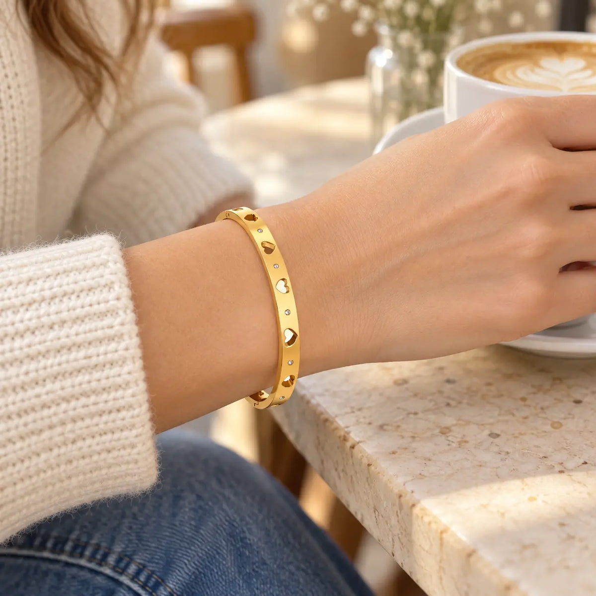 woman wearing heart cutout bangle bracelet with coffee