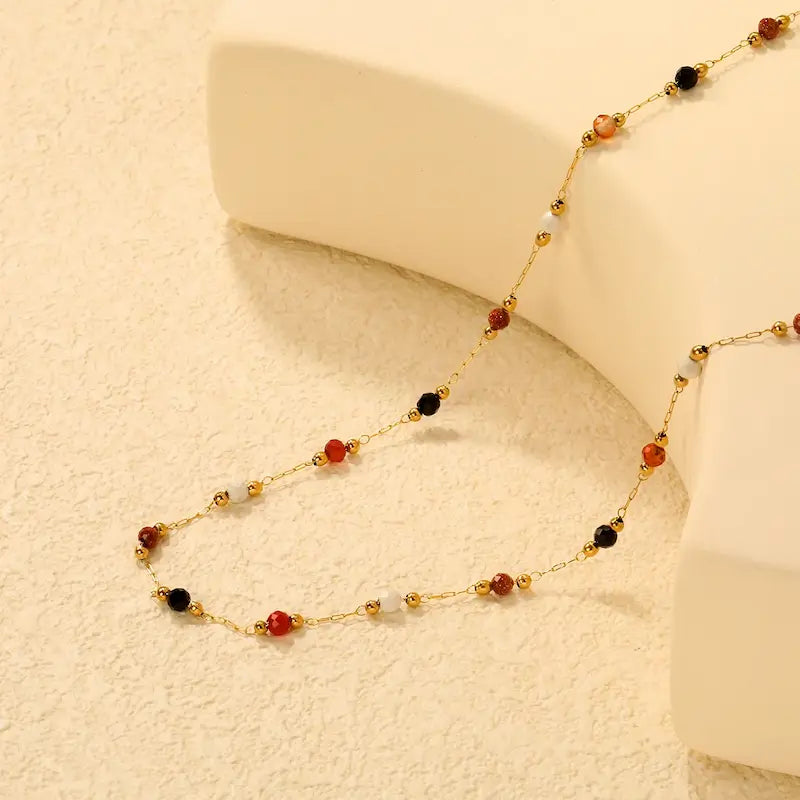 Autumn Confetti 18K gold dainty beaded necklace featuring colorful black, ivory, amber, and rust-colored stones on a delicate gold chain.