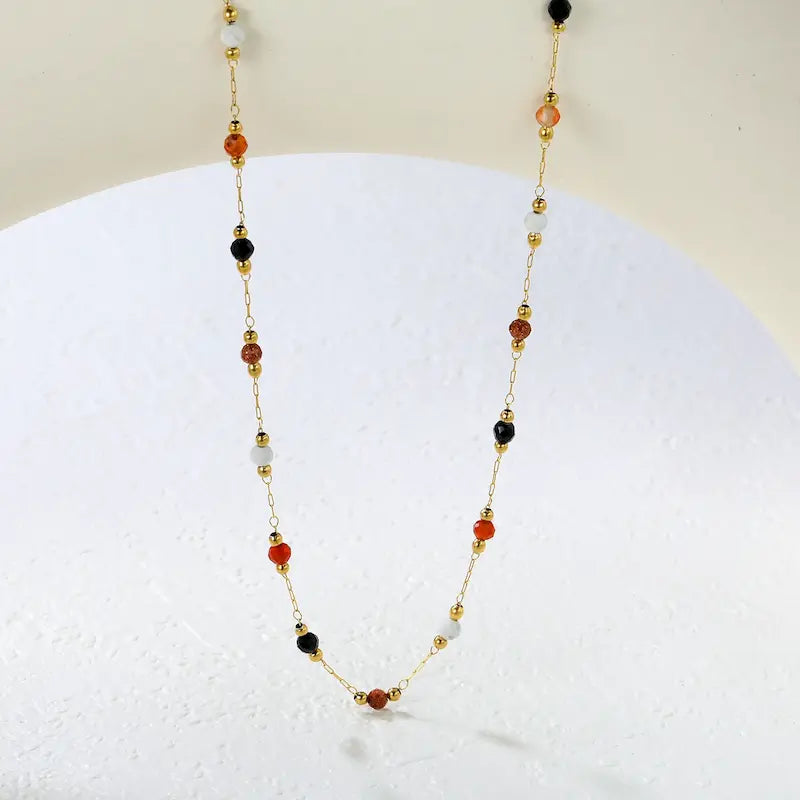 Autumn Confetti 18K gold dainty beaded necklace featuring colorful black, ivory, amber, and rust-colored stones on a delicate gold chain.