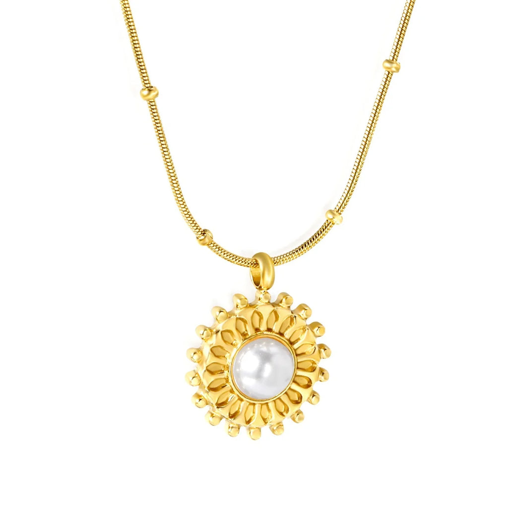 A gold chain necklace featuring a circular pendant with a textured gold sunburst design surrounding a smooth, lustrous white pearl, set against a plain white background.