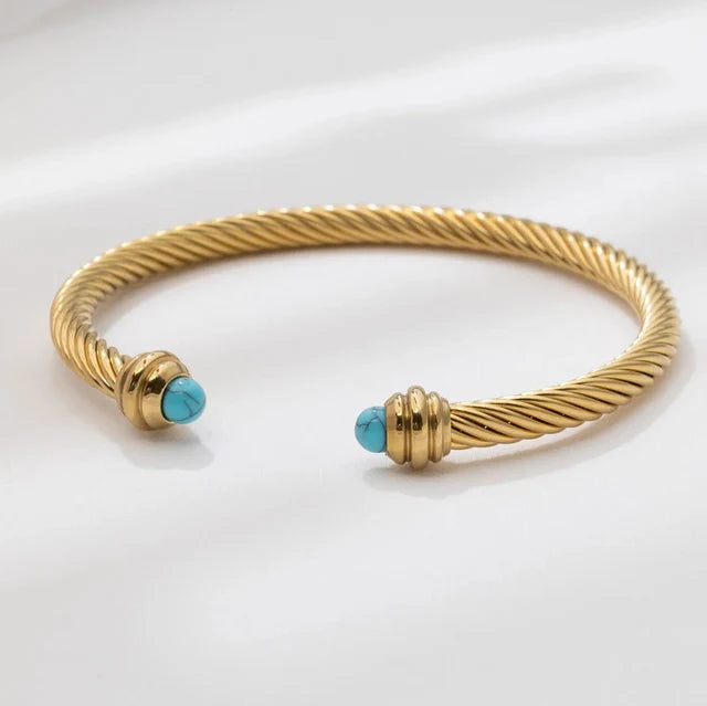Gold bracelet with turquoise beads on a white background