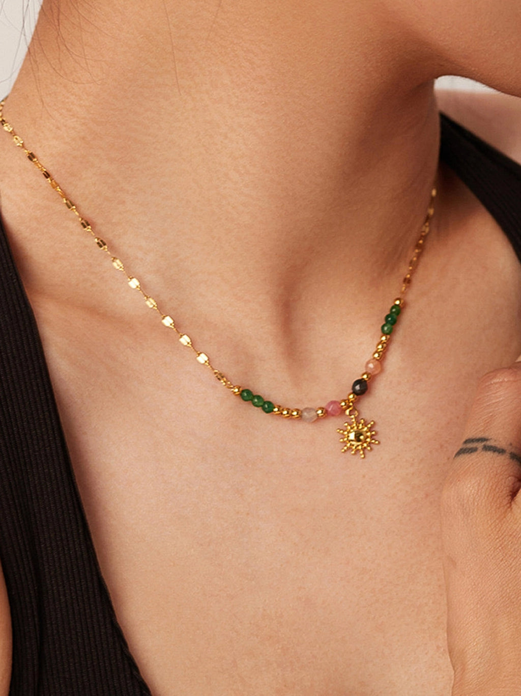 18K gold sun charm necklace with colorful beads shown on a model