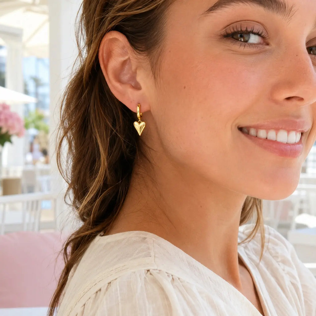 woman wearing heart huggie earrings
